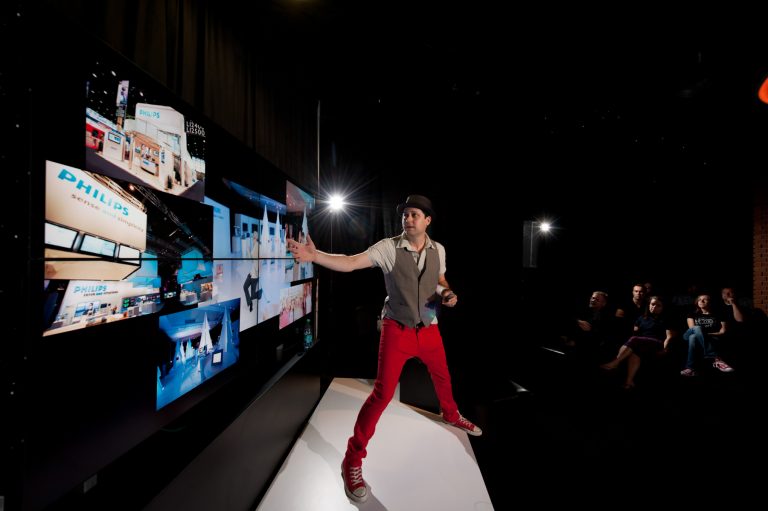 Presenter engaging an audience beside an interactive display at a corporate event